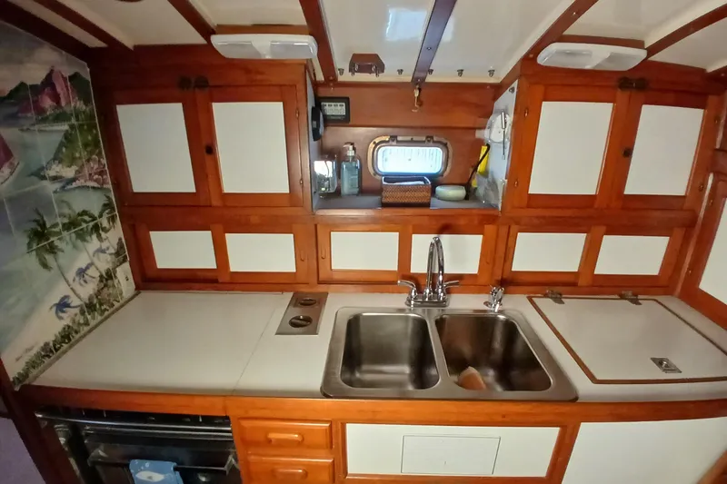 Slide: The Image of 1985 Kadey-Krogen 38 yacht kitchen with dual sinks, wooden cabinets, and nautical decor. - 20