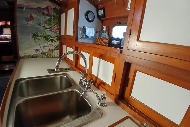 Slide: The Image of 1985 Kadey-Krogen 38 yacht kitchen with dual sinks, wooden cabinets, and nautical-themed wall tiles. - 22