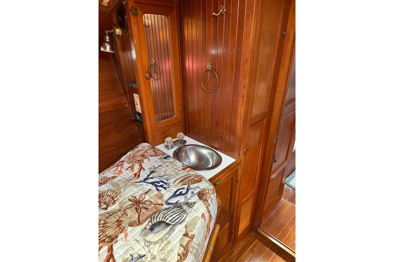 Slide: The Image of 1985 Kadey-Krogen 38 interior with wooden cabinetry, sink, and nautical-themed bedding. - 33