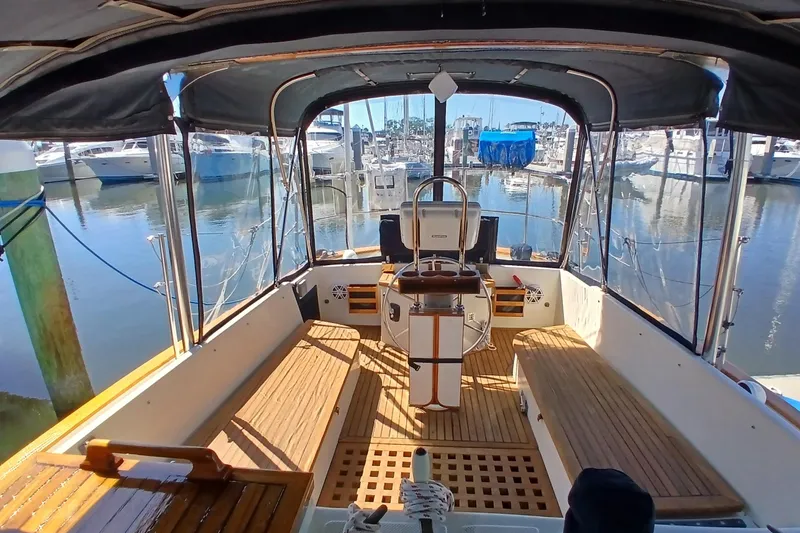 Slide: The Image of Interior view of a 1985 Kadey-Krogen 38 yacht at a marina, showcasing wooden deck and helm. - 49