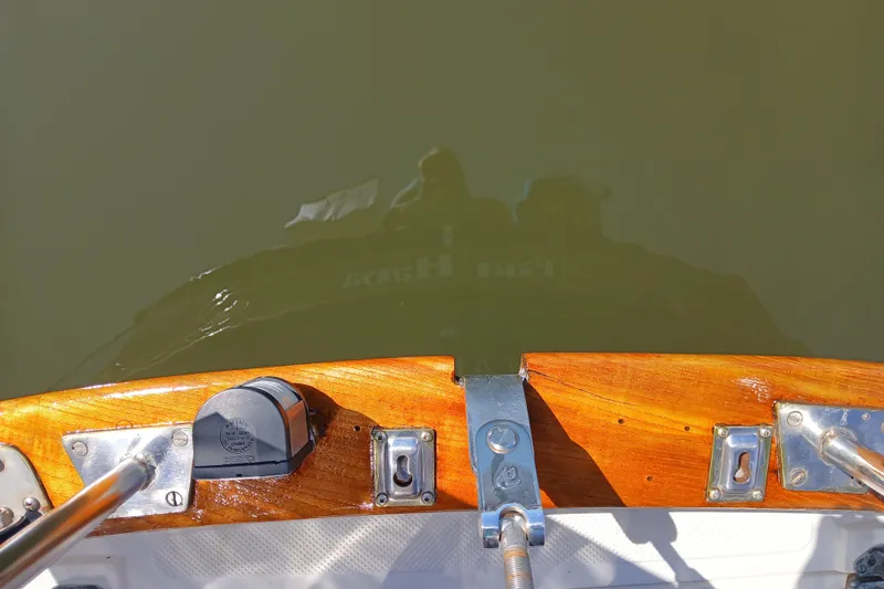 Slide: The Image of 1985 Kadey-Krogen 38 boat stern with polished wood and metal fittings reflected in water. - 72