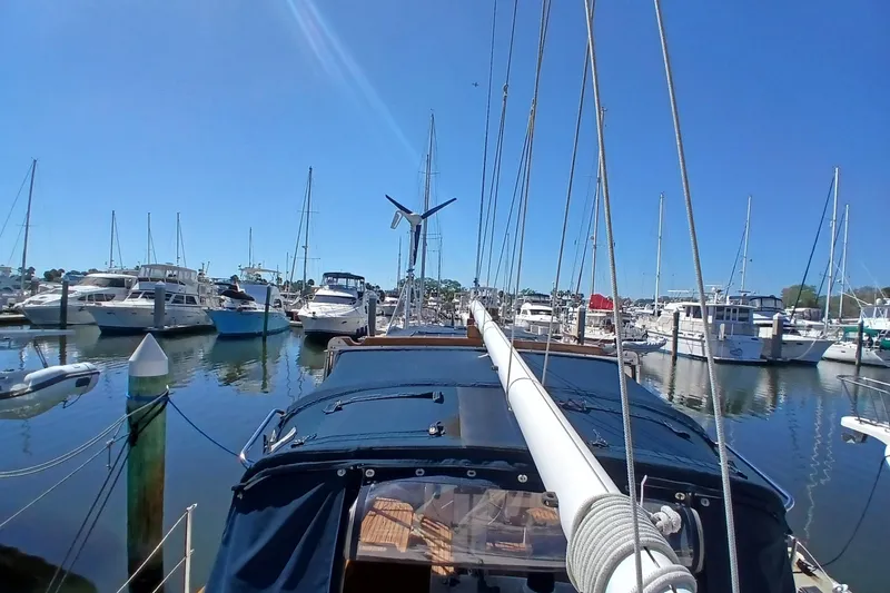 Slide: The Image of 1985 Kadey-Krogen 38 yacht docked in a marina, surrounded by sailboats under a clear blue sky. - 75