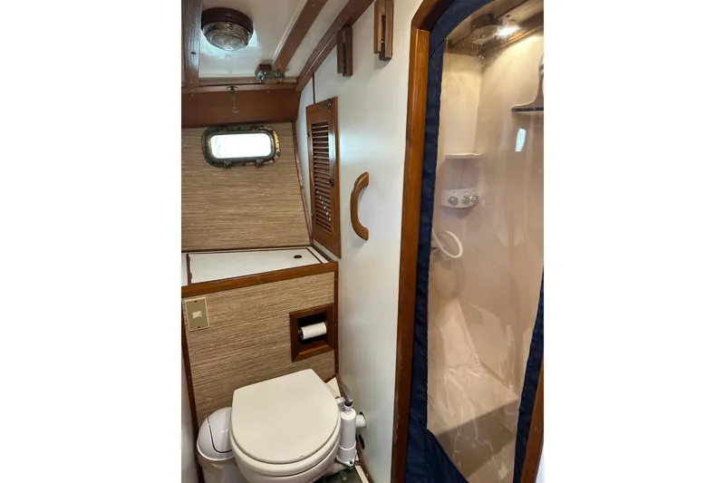 Slide: The Image of 1985 Kadey-Krogen 38 yacht bathroom with toilet, shower, and wooden accents. - 9