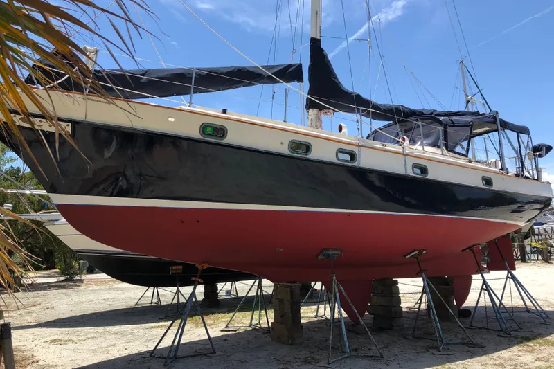 Slide: The Image of 1985 Kadey-Krogen 38 sailboat on stands, black hull, red bottom, sunny day. - 93