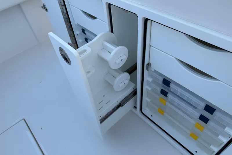 Slide: The Image of Storage compartments on a 2026 Regulator 28 boat, featuring organized tackle boxes and spool holders. - 31
