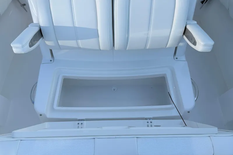Slide: The Image of White seating area on a 2026 Regulator 28 boat, featuring armrests and storage compartment. - 61