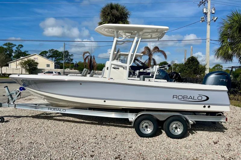 The Image of 2026 Robalo 226 Cayman boat on trailer, parked outdoors under blue sky. - 1