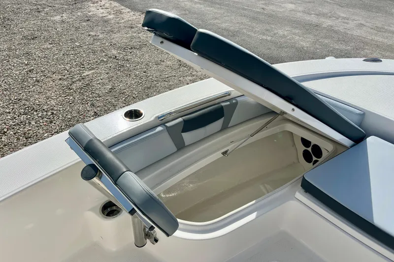 Slide: The Image of 2026 Robalo 226 Cayman boat storage compartment with cushioned seating and cup holder. - 22