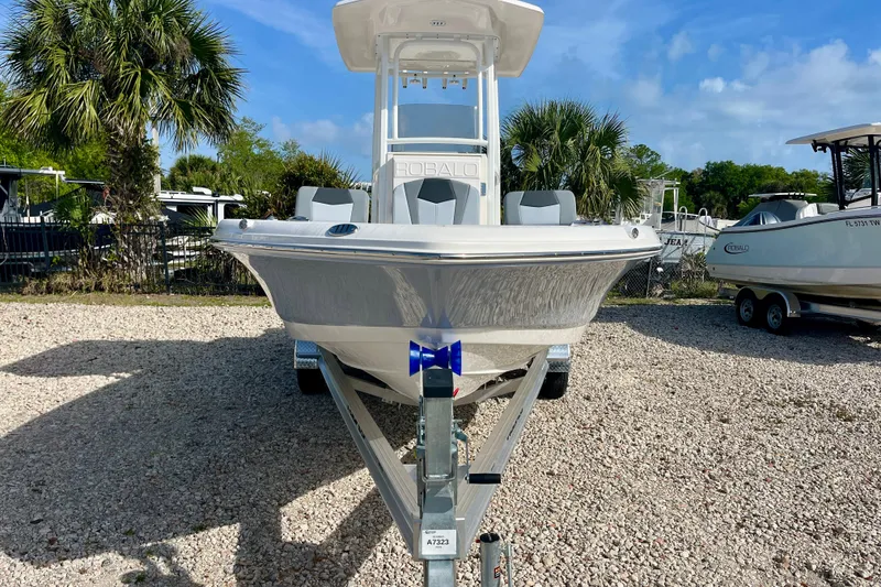 Slide: The Image of 2026 Robalo 226 Cayman boat on trailer, parked outdoors with palm trees. - 3