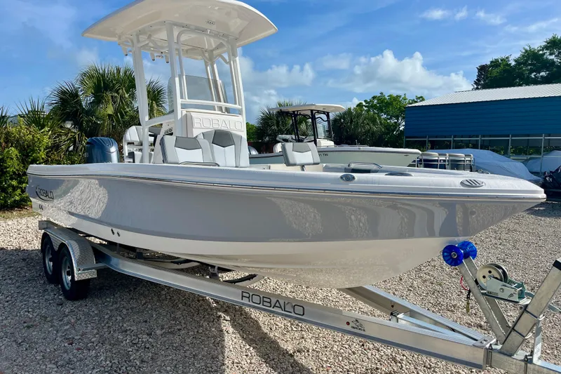 Slide: The Image of 2026 Robalo 226 Cayman boat on trailer, parked outdoors under clear sky. - 4