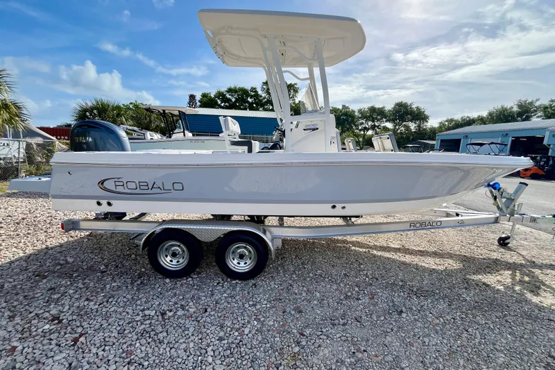 Slide: The Image of 2026 Robalo 226 Cayman boat on trailer, parked outdoors under a clear sky. - 5