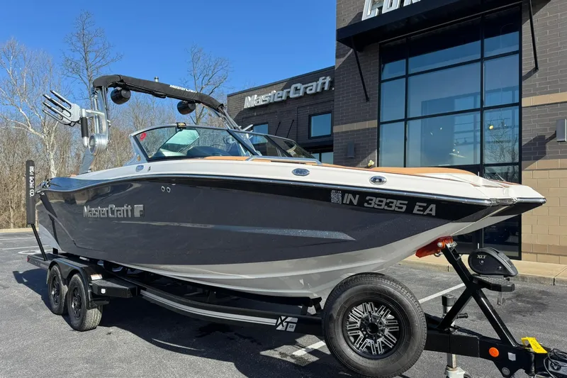 The Image of 2018 MasterCraft XT22 boat on trailer, parked outside dealership on a sunny day. - 0