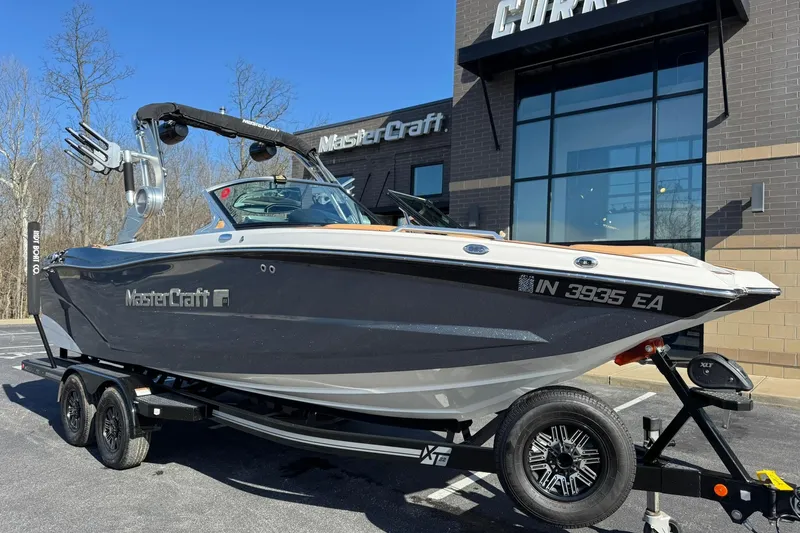 Slide: The Image of 2018 MasterCraft XT22 boat on trailer outside dealership, sunny day. - 24