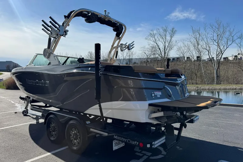 Slide: The Image of 2018 MasterCraft XT22 boat on trailer, parked near a lake under clear skies. - 5
