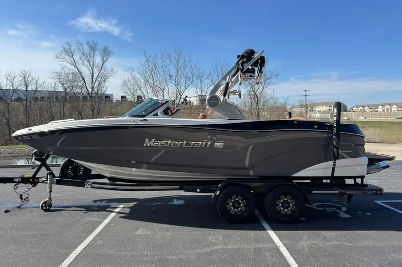 Slide: The Image of 2018 MasterCraft XT22 boat on trailer in parking lot, clear sky background. - 6