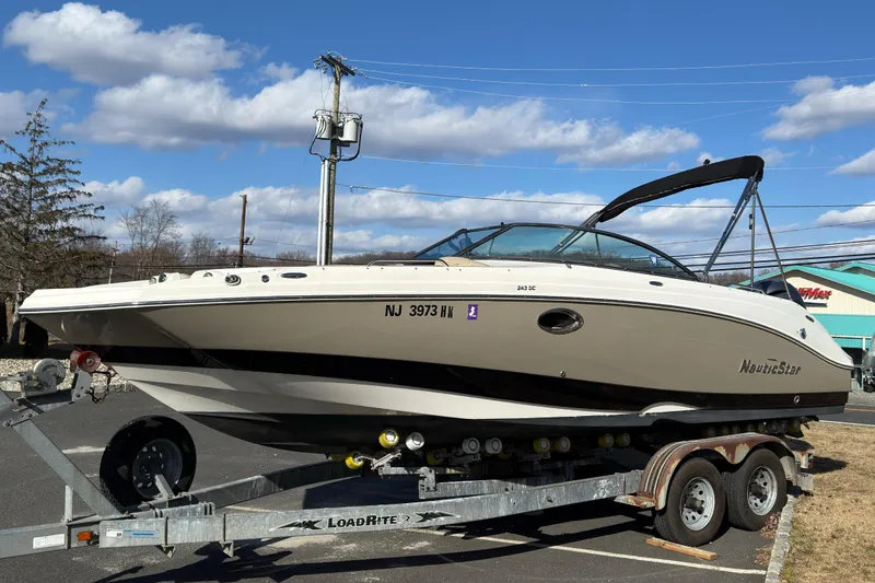 The Image of 2017 NauticStar 243DC Sport Deck boat on trailer under blue sky. - 0