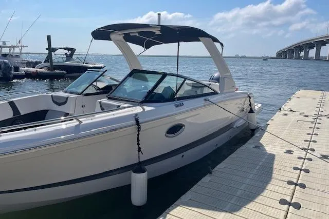 Slide: The Image of 2023 Chaparral 270 OSX boat docked by the water under a clear sky. - 1
