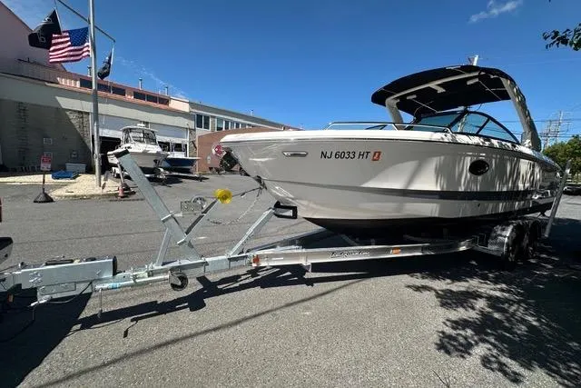 Slide: The Image of 2023 Chaparral 270 OSX boat on trailer, parked on street under clear blue sky. - 10