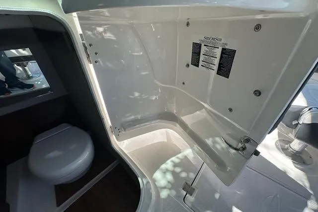 Slide: The Image of 2023 Chaparral 270 OSX boat interior with toilet and storage compartment. - 33