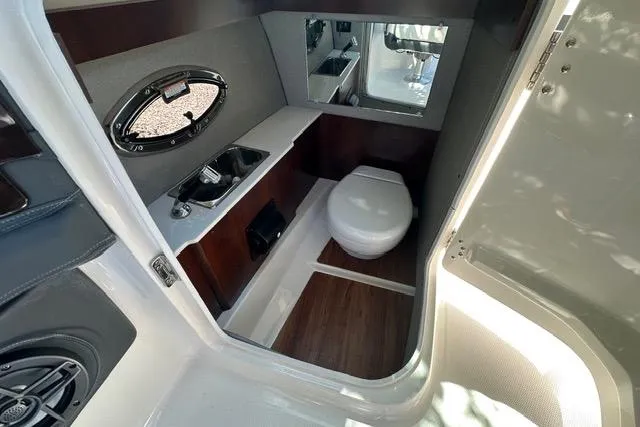 Slide: The Image of 2023 Chaparral 270 OSX boat interior with compact bathroom and modern amenities. - 36