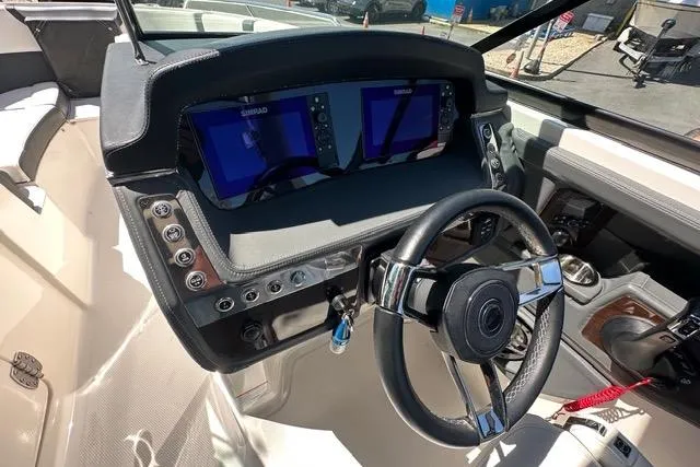 Slide: The Image of 2023 Chaparral 270 OSX boat dashboard with dual Simrad displays and steering wheel. - 38