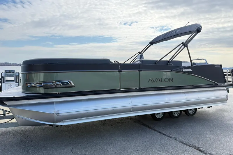 The Image of 2026 Avalon Catalina Elite 23 pontoon boat docked under a cloudy sky. - 1