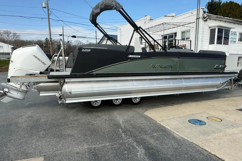 Slide: The Image of 2026 Avalon Catalina Elite 23 pontoon boat with Mercury outboard engine, parked on a trailer. - 5