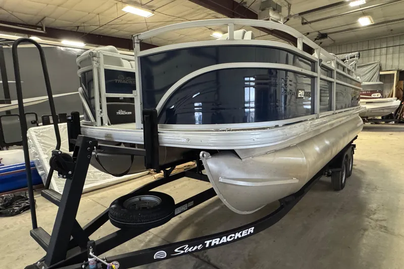 The Image of 2026 Sun Tracker SportFish 20 DLX pontoon boat on trailer in indoor storage. - 1