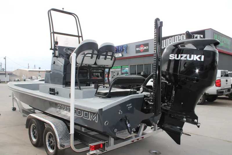 Slide: The Image of 2026 Freedom Boats 24 Defender with Suzuki engine on trailer, parked outside dealership. - 15