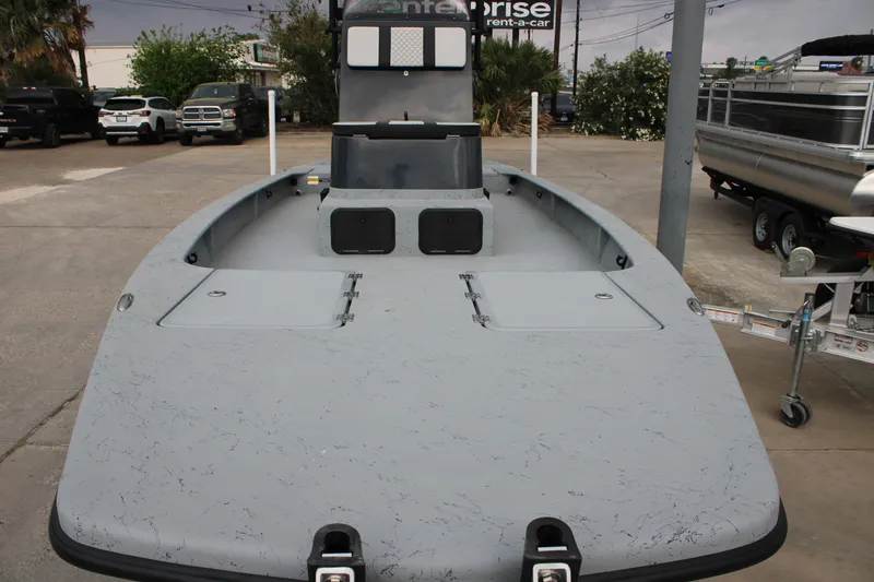 Slide: The Image of 2026 Freedom Boats 24 Defender, gray deck, parked outdoors with vehicles in background. - 21
