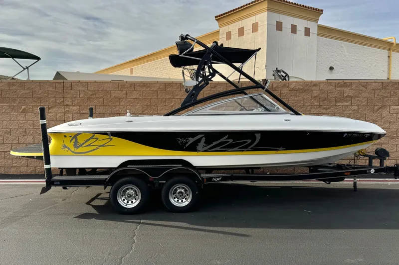The Image of 2006 Tigé 22V boat on trailer, featuring sleek black and yellow design. - 0