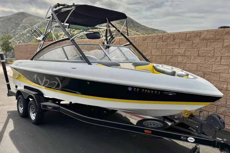 Slide: The Image of 2006 Tigé 22V boat on trailer, black and yellow design, parked outdoors. - 1