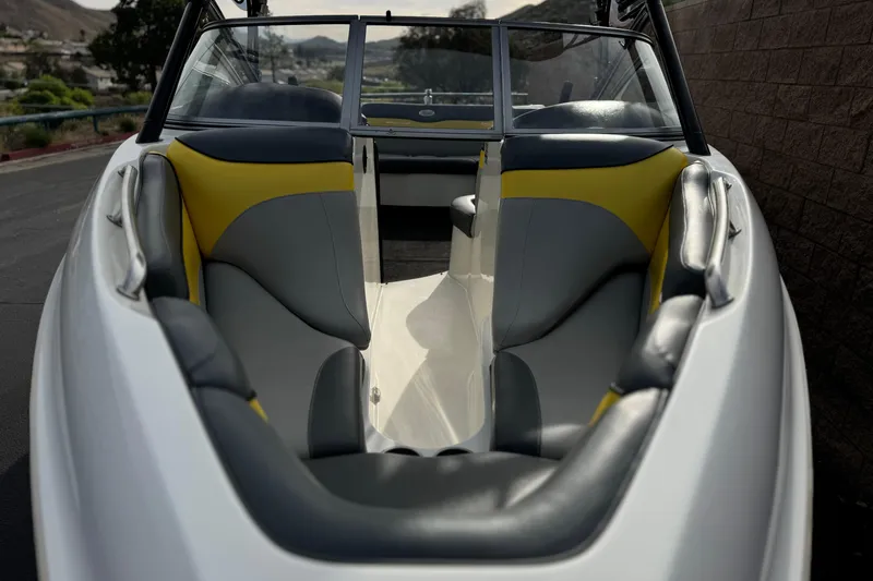 Slide: The Image of 2006 Tigé 22V boat interior with yellow and gray seating, parked outdoors. - 10