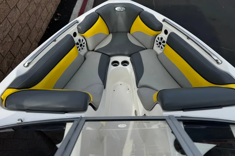 Slide: The Image of 2006 Tigé 22V boat interior with gray and yellow seating, cup holders, and speakers. - 11