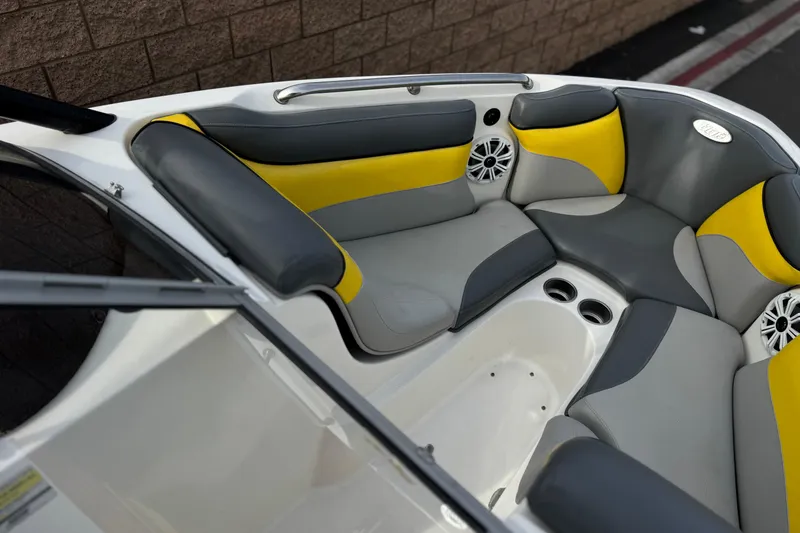 Slide: The Image of 2006 Tigé 22V boat interior with gray and yellow seating, cup holders, and speakers. - 12
