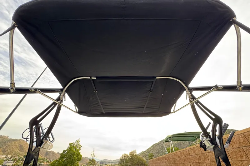 Slide: The Image of 2006 Tigé 22V boat with black bimini top, viewed from below against a cloudy sky. - 15