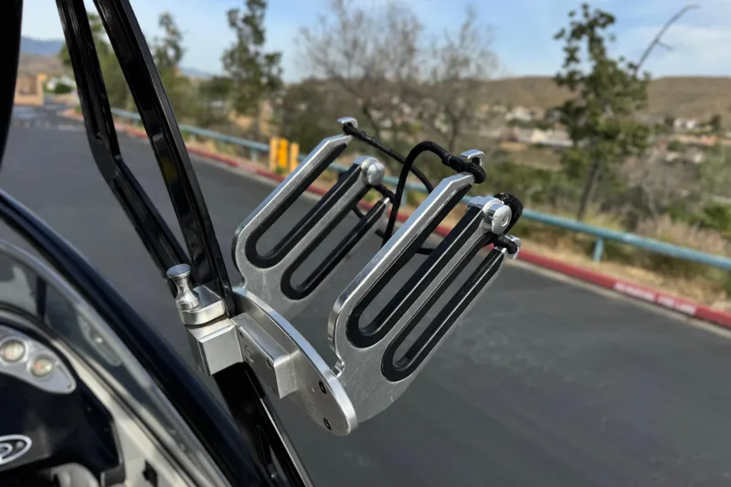 Slide: The Image of Wakeboard rack on a 2006 Tigé 22V boat, parked on a scenic road. - 17