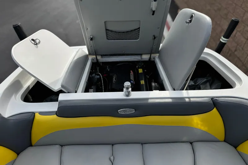 Slide: The Image of 2006 Tigé 22V boat engine compartment with open hatches and gray-yellow seating. - 21