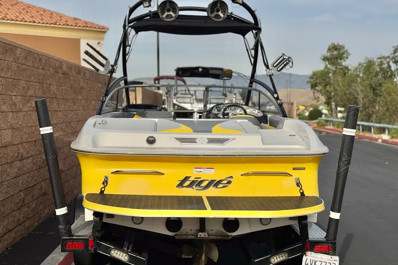 Slide: The Image of 2006 Tigé 22V yellow boat with wakeboard tower, parked on a trailer. - 4