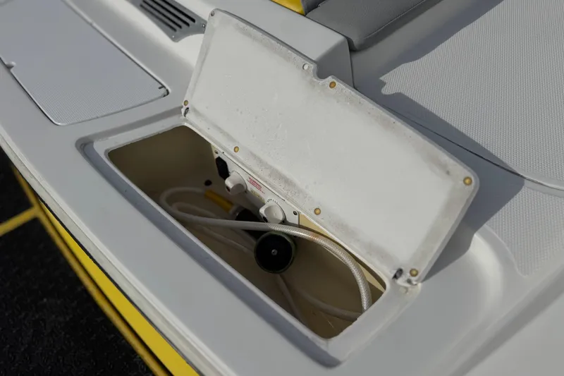 Slide: The Image of Open storage compartment on a 2006 Tigé 22V boat, showing hoses and fittings. - 7