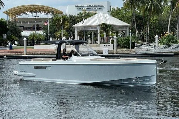 Slide: The Image of 2023 Fjord 38 Xpress boat cruising near a waterfront pavilion. - 2