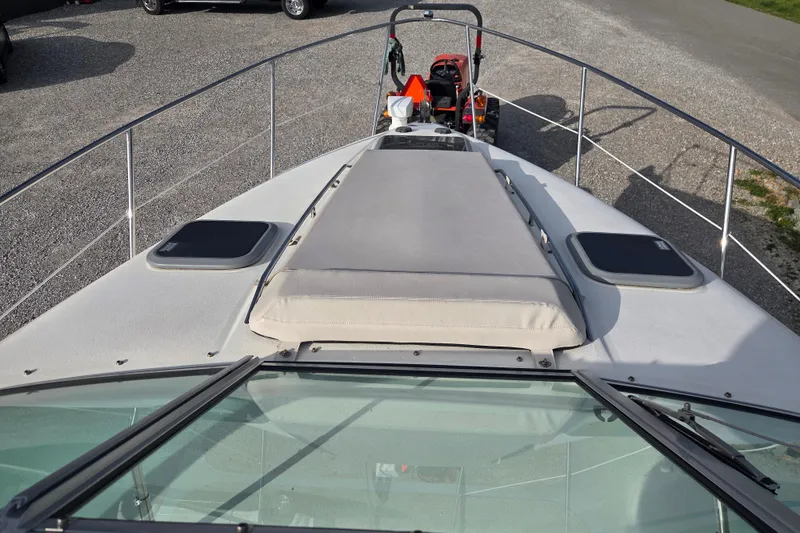 Slide: The Image of 2001 Doral 270 SC boat deck with sunpad and railing, parked on gravel. - 12