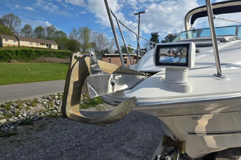 Slide: The Image of 2001 Doral 270 SC boat with anchor and spotlight, parked on gravel near green landscape. - 13