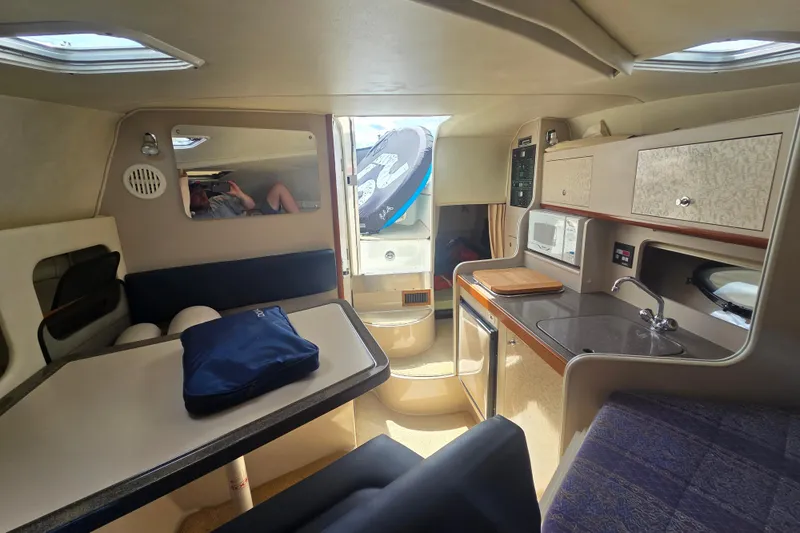 Slide: The Image of Interior of a 2001 Doral 270 SC boat featuring a kitchenette and seating area. - 14