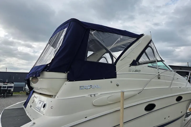 Slide: The Image of 2001 Doral 270 SC boat with blue canopy, docked under cloudy skies. - 25