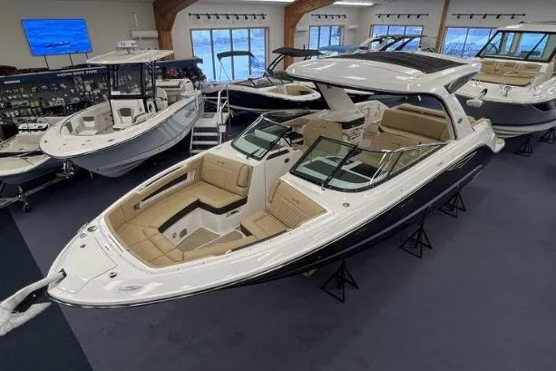 The Image of 2024 Sea Ray SLX 310 luxury boat displayed in a showroom with elegant seating. - 0