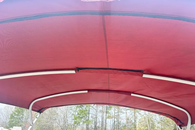 Slide: The Image of Red canopy of a 2022 Bentley Pontoons 220 Navigator boat against a forest backdrop. - 5