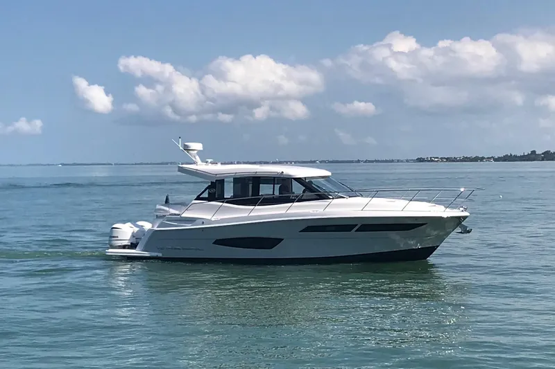 The Image of 2021 Regal 38 XO yacht cruising on calm blue waters under a partly cloudy sky. - 0