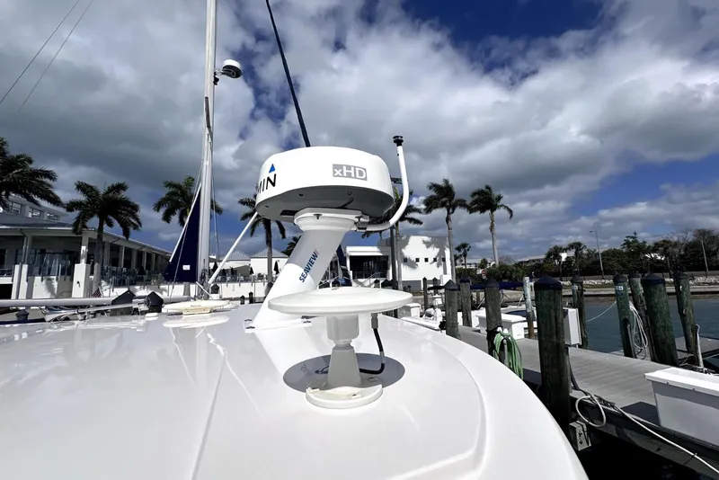 Slide: The Image of 2021 Regal 38 XO yacht docked, featuring Garmin radar, palm trees, and cloudy sky. - 13