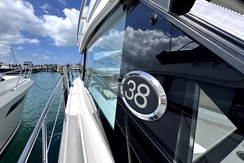 Slide: The Image of 2021 Regal 38 XO yacht docked, showcasing sleek design and reflective windows under a blue sky. - 15
